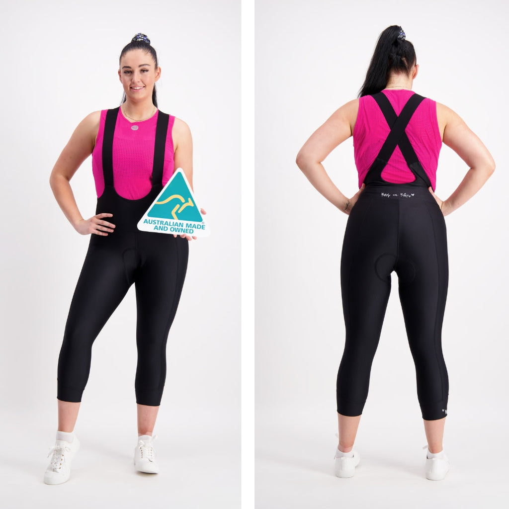 back and front views of model wearing a pink base layer and capri length black cycling bibs