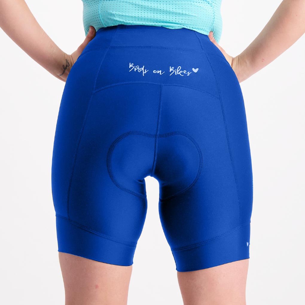 Back view of ocean blue short padded cycling pants showing reflective Birds on Bikes logo